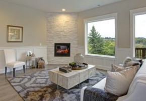 Relaxing white living room features corner stone fireplace lined with tan walls accented with lower wall white wainscoting framing large windows with gorgeous view.